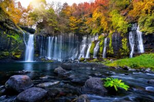 Multi-Tiered Waterfall Flowing Into Rocky Pool Surrounded By Autumn Forest